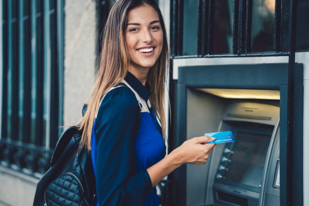 Smiling woman at the ATM ready to withdraw cash money   ++++ Note for the inspector: Credit card is fake ++++